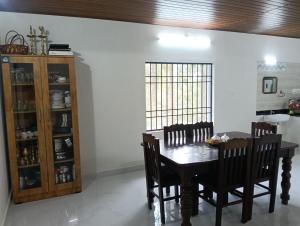 a dining room with a wooden table and chairs at Anurastays in Mudigere