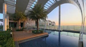 a building with a pool with palm trees in it at The Onnut Nest 1BR Sofa Bed Onnut BTS 50m in Bangkok