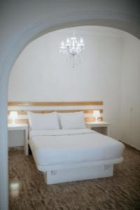 ein weißes Schlafzimmer mit einem weißen Bett und einem Kronleuchter in der Unterkunft Hotel Thirasia in Fira + 36 Fotos
