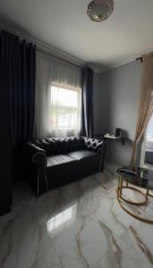 a black couch in a living room with a window at Uduak Lodge in Harare +4 photos
