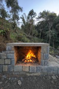 a brick fireplace with a fire in it at Chara Farmhouse in Kohīma