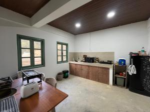 a large kitchen with a table and a refrigerator at Chara Farmhouse in Kohīma