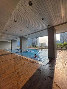 two people swimming in a swimming pool in a building at 8 Adriatico Condominium 1BR in Sampong