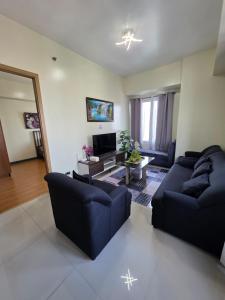a living room with two blue couches and a tv at 8 Adriatico Condominium 1BR in Sampong