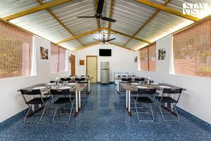 een eetkamer met tafels en stoelen en een plafond bij StayVista at Jims Farmstay with Pool, Pet-friendly in Halgūr