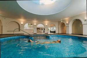 two people swimming in a pool in a building at Hestia Hotel Strand in Pärnu