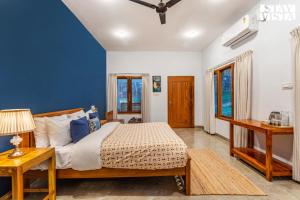 een slaapkamer met een groot bed met blauwe muren bij StayVista at Jims Farmstay with Pool, Pet-friendly in Halgūr +29 foto's