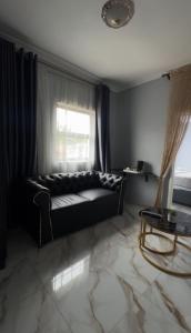 a black couch in a living room with a window at Uduak Lodge in Harare