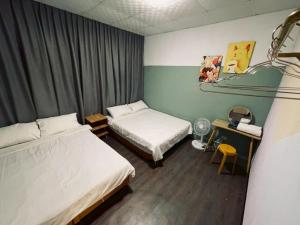 a small room with two beds and a desk with a desk at Mumian Manlv Homestay in Hengchun South Gate
