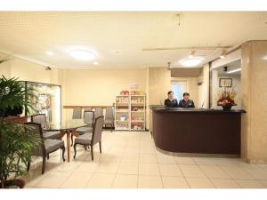 two people sitting at a counter in a restaurant at Chofu Urban Hotel in Chofu