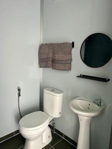 a white bathroom with a toilet and a sink at TeeDo Zzz in Parit Buntar +8 photos