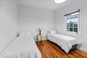 two beds in a white room with a window at Cottage on Carthage in Tamworth
