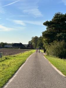 due persone che vanno in bicicletta lungo una strada accanto a un campo di De Hombrake, Bed & Breakfast a Wilp