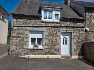 een stenen huis met een witte deur en ramen bij Maison Bretagne Authentique in Plémy