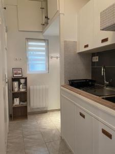 a kitchen with white cabinets and a sink and a window at Duplex charmant centre Joigny - 1 in Joigny