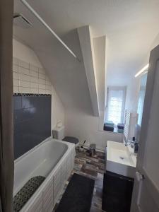 een witte badkamer met een bad en een wastafel bij Maison Bretagne Authentique in Plémy