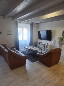 een woonkamer met twee banken en een tv bij Maison Bretagne Authentique in Plémy