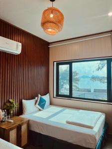 een slaapkamer met een groot bed en een raam bij Woodstock Beach Camp in Cat Ba