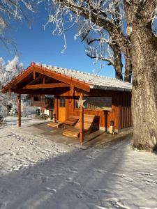 a small wooden cabin in the snow next to a tree at Summererhof Hausham in Hausham