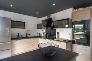 a kitchen with wooden cabinets and a black counter top at Gîte Perce Neige, Spa, Sauna in Gerbépal