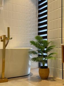 een badkamer met een bad en een plant in een pot bij Ambassadori Kachreti Golf Resort, Villa 40 in Kachretʼi