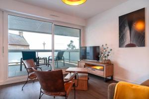 ein Wohnzimmer mit Fernseher und Tisch und Stühlen in der Unterkunft La Proue - Appartement vue mer in Concarneau