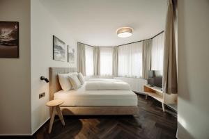 a white bedroom with a bed and a television at Hotel loj - our kind of place in Flachau +32 photos