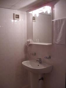 a white bathroom with a sink and a mirror at Hotel Velbazhd in Kyustendil