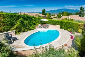 a swimming pool with chairs and an umbrella in a yard at Gîte au Ventoux in Villes-sur-Auzon