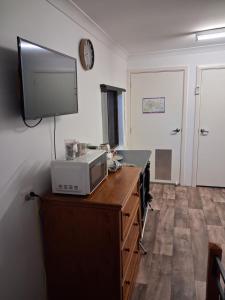 a kitchen with a microwave and a tv on the wall at Cartledge Ave studio and house homestay in Whyalla