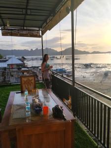 une femme debout sur un balcon donnant sur la plage dans l'établissement Bajo Komodo Homestay, à Komodo