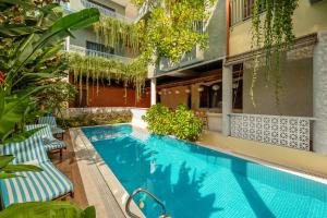 a swimming pool with two chairs next to a building at La ALBA Beach Villa in Hoi An
