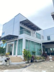 a white building with plants in front of it at Cozy Stay in Ban Nong Waeng