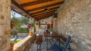 een stenen patio met een houten tafel en stoelen bij Rustic villa Pietro with panoramic view in Motovun in Motovun