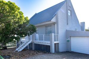 a white house with a porch and a garage at Joan's Sea Cottage in Pringle Bay