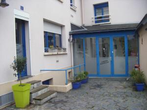 un bâtiment avec une porte bleue et quelques plantes en pot dans l'établissement Auberge Armoricaine, à Louisfert