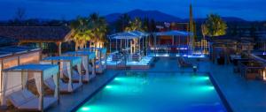 a hotel pool with chairs and umbrellas at night at Tresort Oil Glamping in Principina Terra