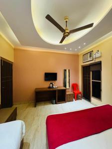Schlafzimmer mit einem Bett, einem Deckenventilator und einem Schreibtisch in der Unterkunft Jaiswal Dharmshala in Sultānpur