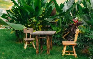 Twee houten tafels en stoelen staan in het gras. bij Nong Lam Ecolodge in Linh Xuân Thôn