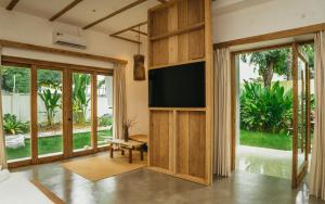 a living room with a flat screen tv and sliding glass doors at Nong Lam Ecolodge in Linh Xuân Thôn