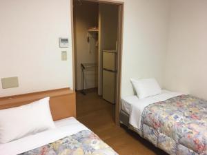 a small room with two beds and a mirror at Hotel Tajimi Hills Myroom in Tajimi