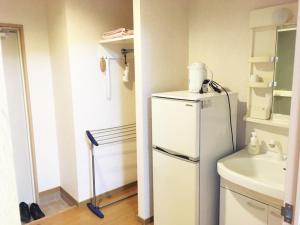 a kitchen with a white refrigerator and a sink at Hotel Tajimi Hills Myroom in Tajimi