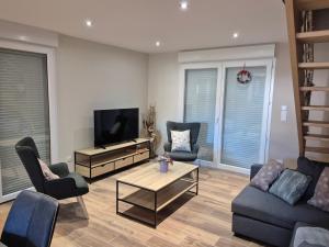 a living room with a couch and a tv and chairs at Maison Gite Le Randonneur in La Bresse