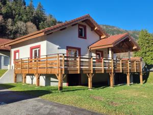 a house with a large wooden deck in front of it at Maison Gite Le Randonneur in La Bresse