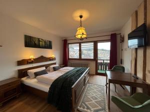 ein Schlafzimmer mit Bett, Schreibtisch und Fernseher in der Unterkunft Hotel Bergfreiheit 7 in Schonach