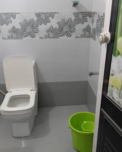 a bathroom with a toilet and a green bucket at UPPU HOMESTAY in Mulappilangād