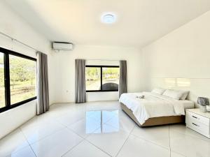a white bedroom with a bed and a window at Amuji Accommodation and Apartments in Vilanculos