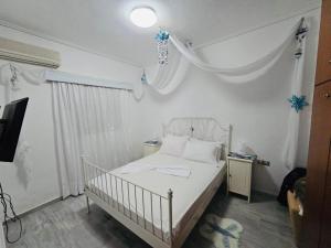 a white bedroom with a white bed and a window at Mani Beach House in Vathia