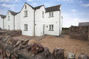 een wit huis met een stenen muur bij 4 Bed in Port Eynon oc-hh9901 in Port-Eynon