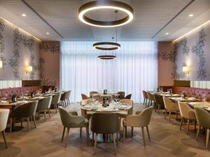 a restaurant with tables and chairs and a large window at Mövenpick Hotel Stuttgart Messe & Congress in Stuttgart